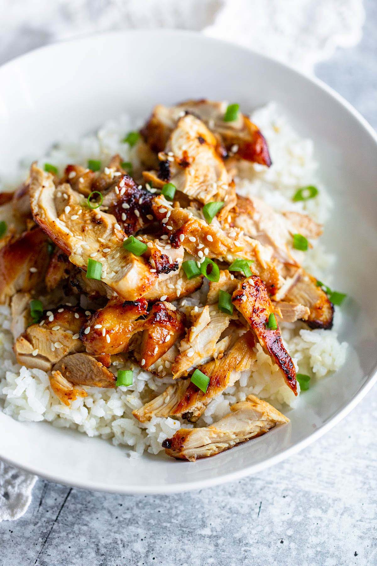 sliced chicken thighs served on top of a bed of rice topped with green onions