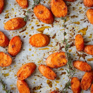 roasted carrots on a cookie sheet with sprigs of thyme