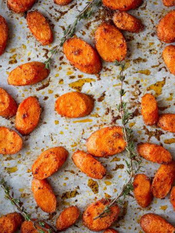 roasted carrots on a cookie sheet with sprigs of thyme