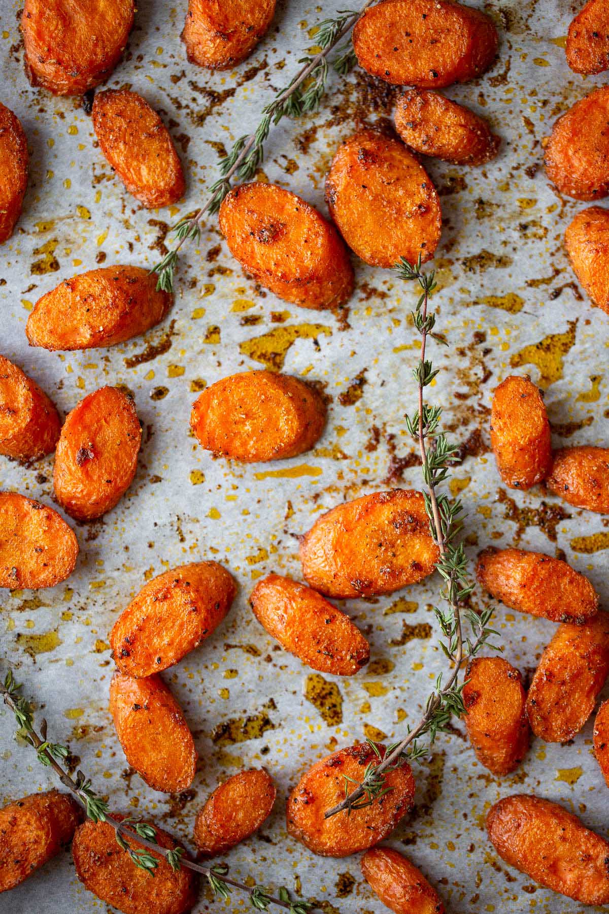roasted carrots on a cookie sheet with sprigs of thyme