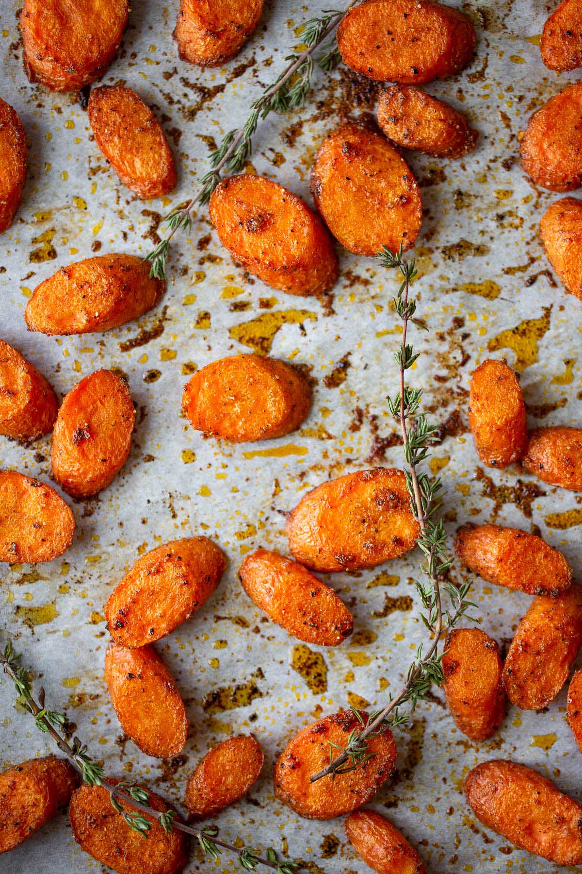 roasted carrots on a cookie sheet with sprigs of thyme.