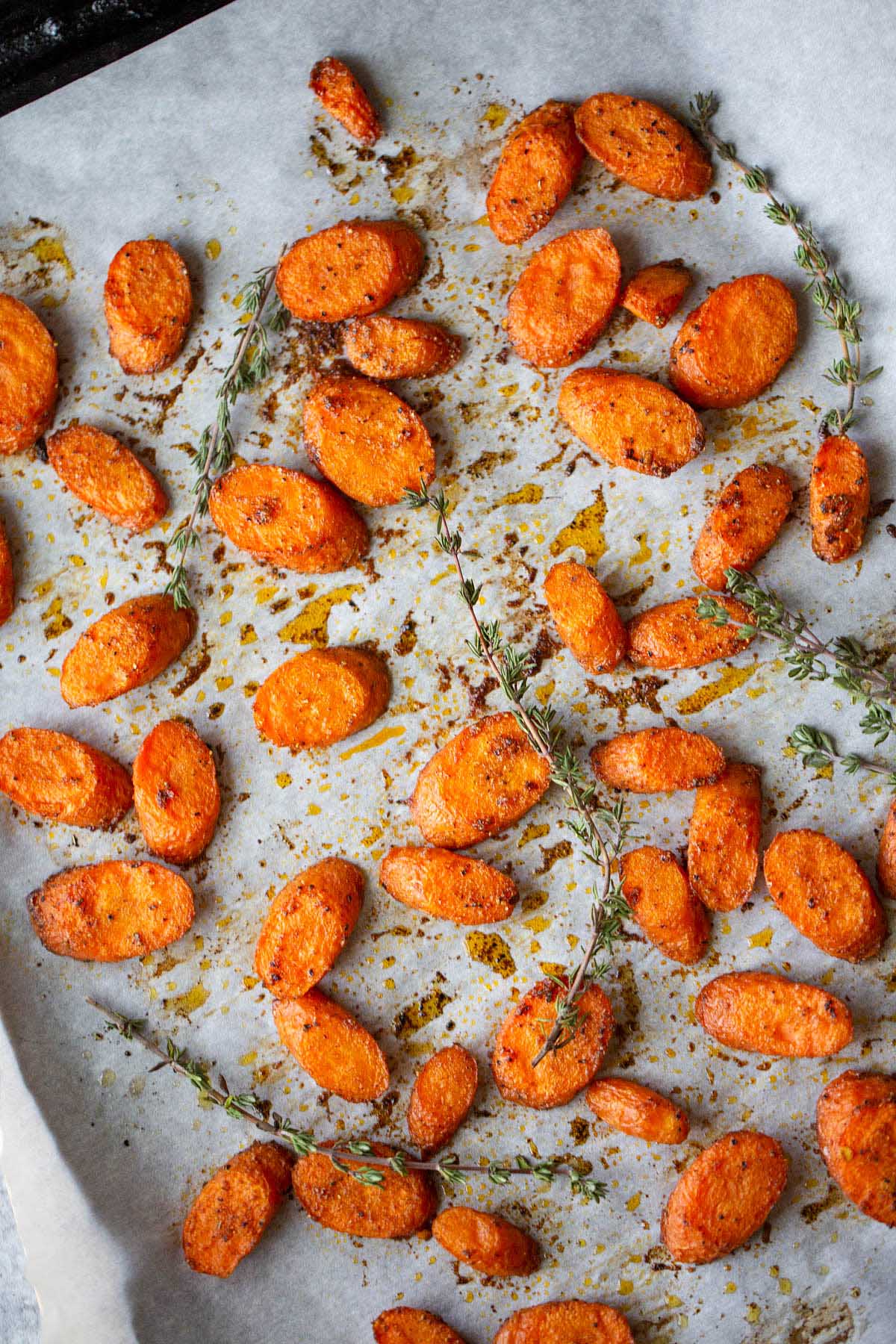 roasted carrots on a cookie sheet with sprigs of thyme.