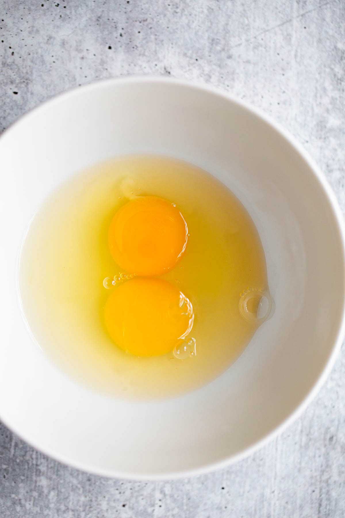 two cracked eggs in a white bowl