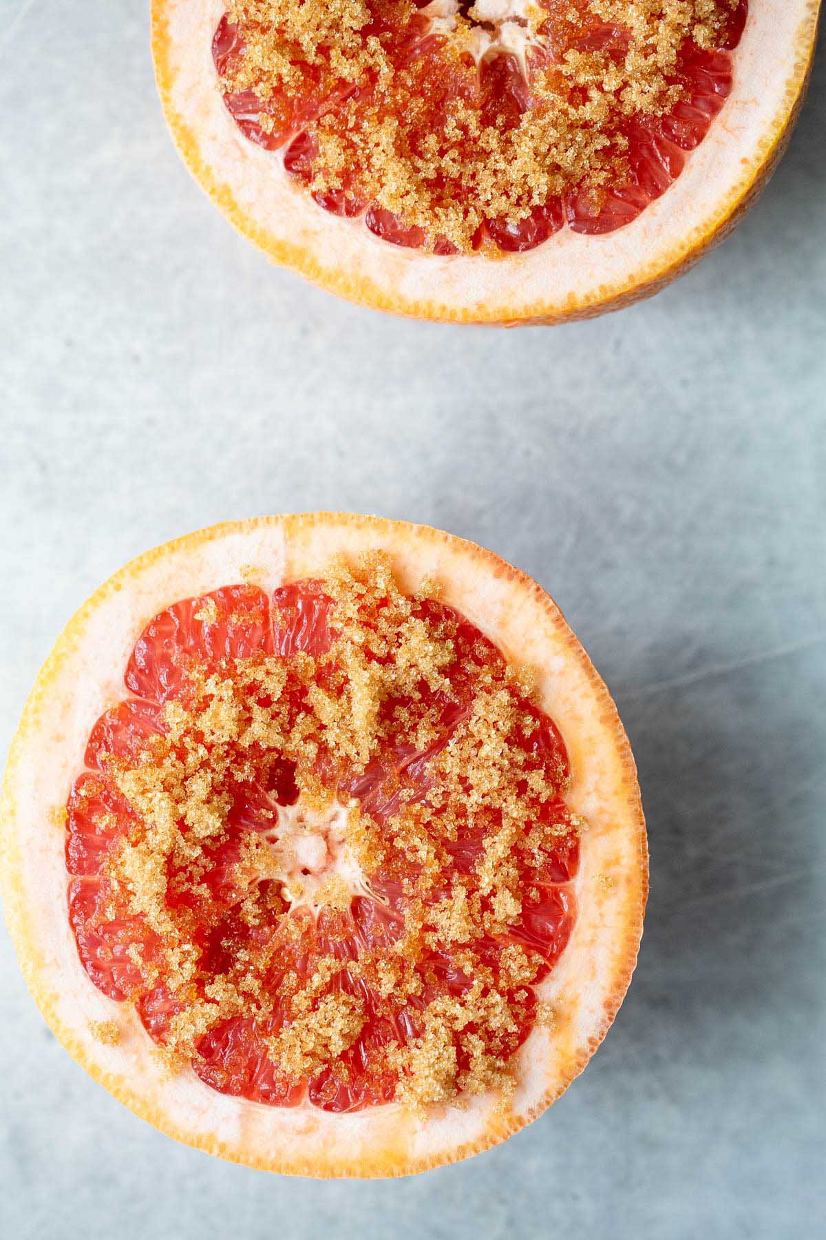 uncooked grapefruit with brown sugar sprinkled on top.