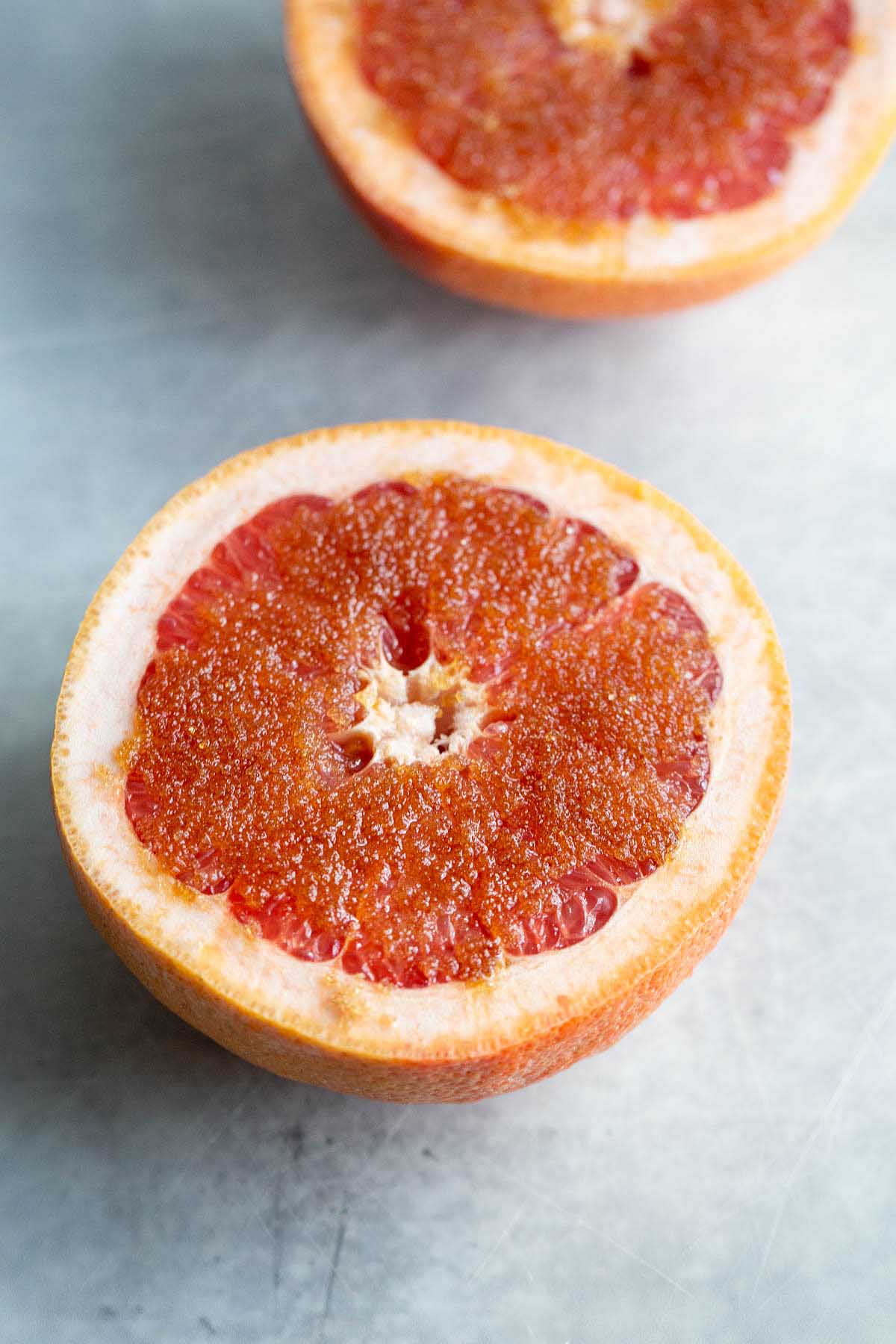 uncooked grapefruit with brown sugar sprinkled on top.