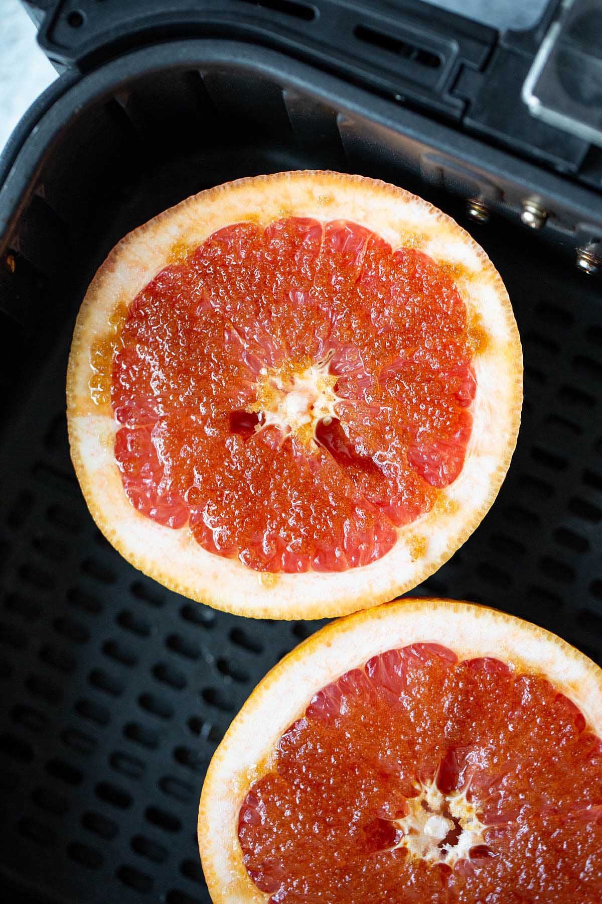 uncooked grapefruit halves in air fryer basket