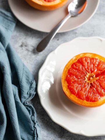 cooked grapefruit on plates with a blue towel on the side.