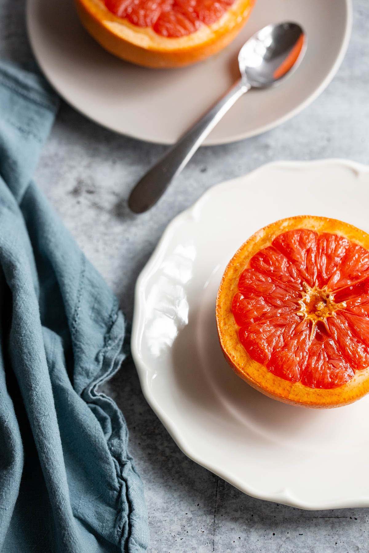 cooked grapefruit on plates with a blue towel on the side.