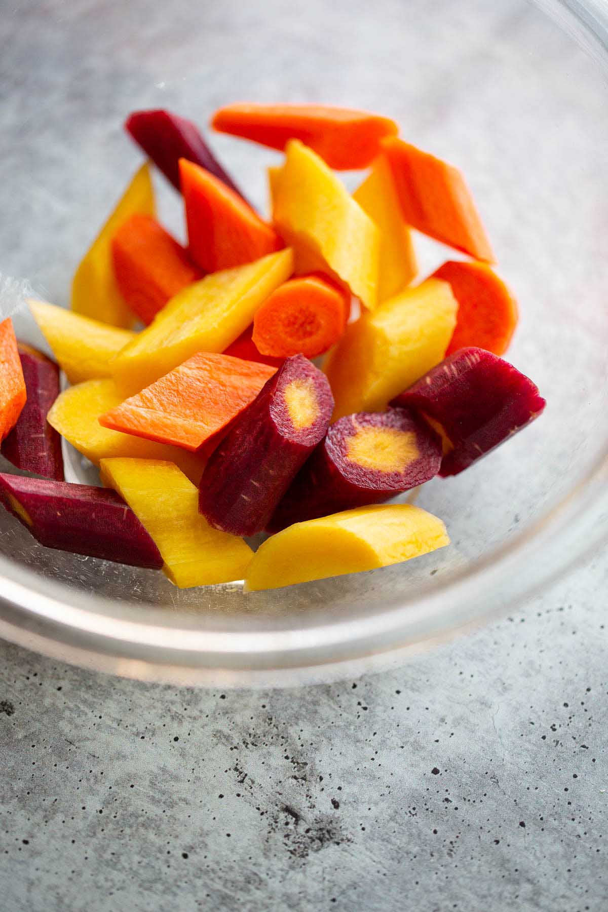 Sliced rainbow carrots in a glass bowl.