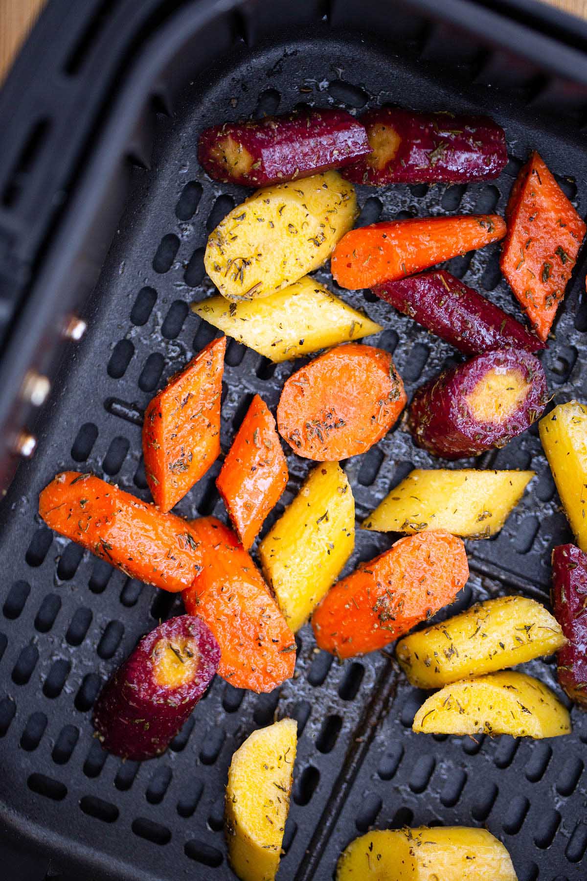 sliced rainbow carrots in air fryer basket.