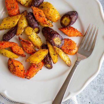 Cooked rainbow carrots on a plate.