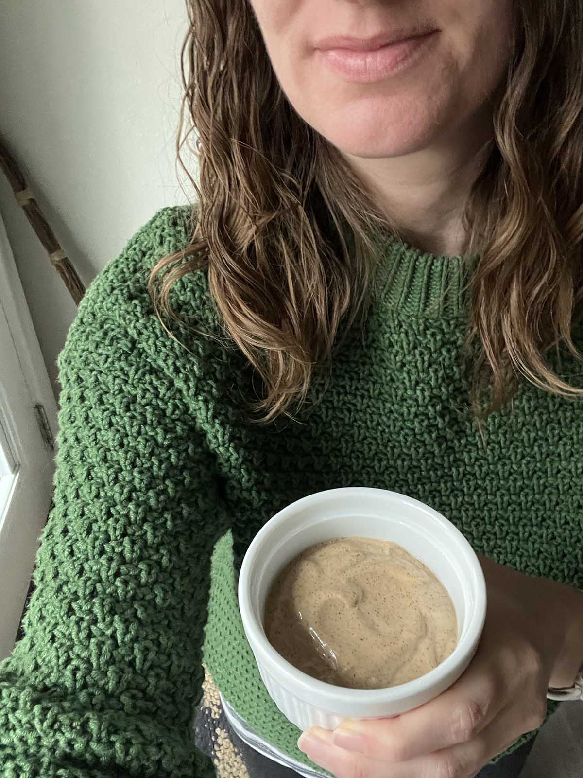 chipotle mayo in a bowl held by a girl in a green sweater.