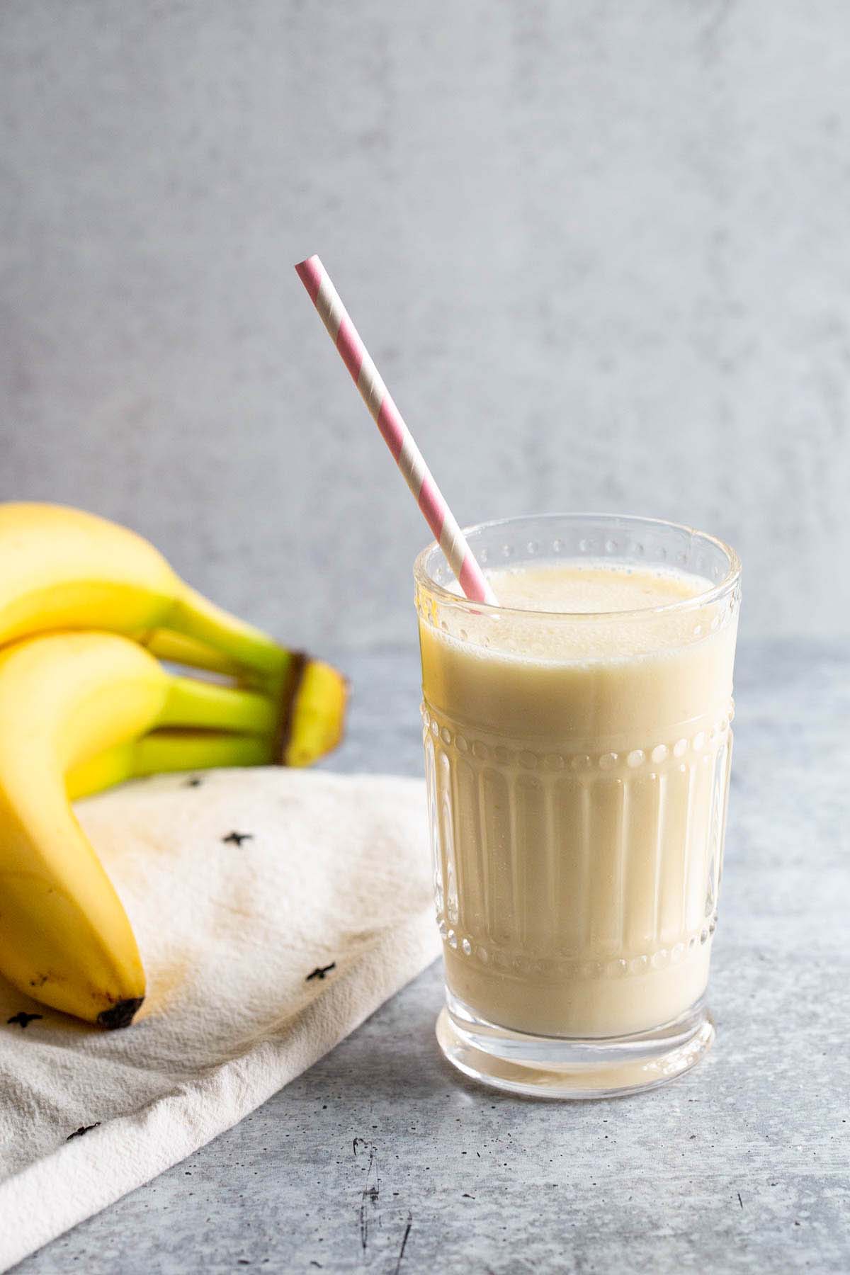 Smoothie in a glass with bananas in the background.