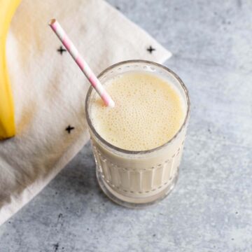Smoothie in a glass with a pink and white straw.