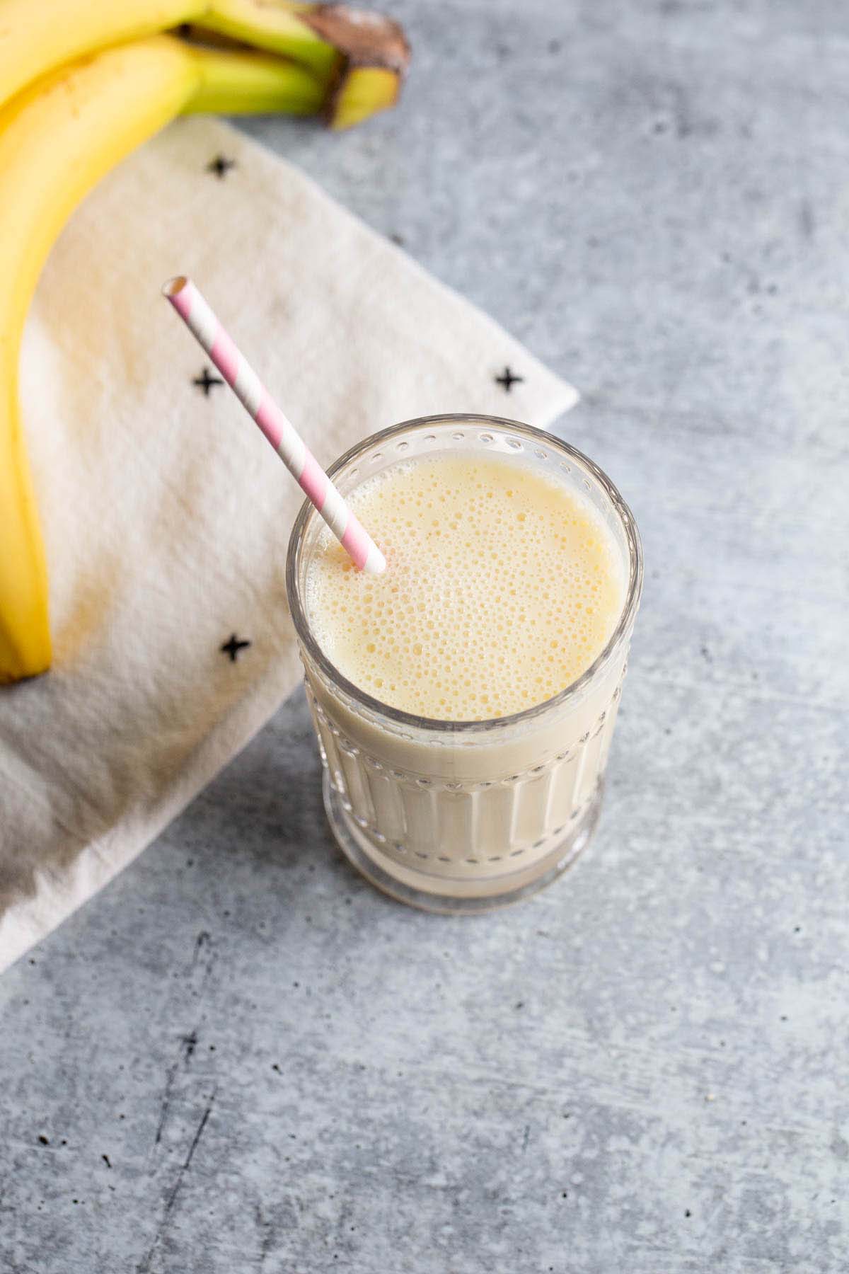 Smoothie in a glass with a pink and white straw.