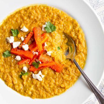 Red lentil dal topped with carrots, cilantro, and feta.
