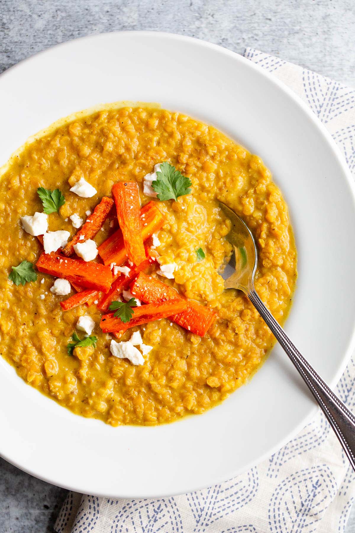 Red lentil dal topped with carrots, cilantro, and feta.