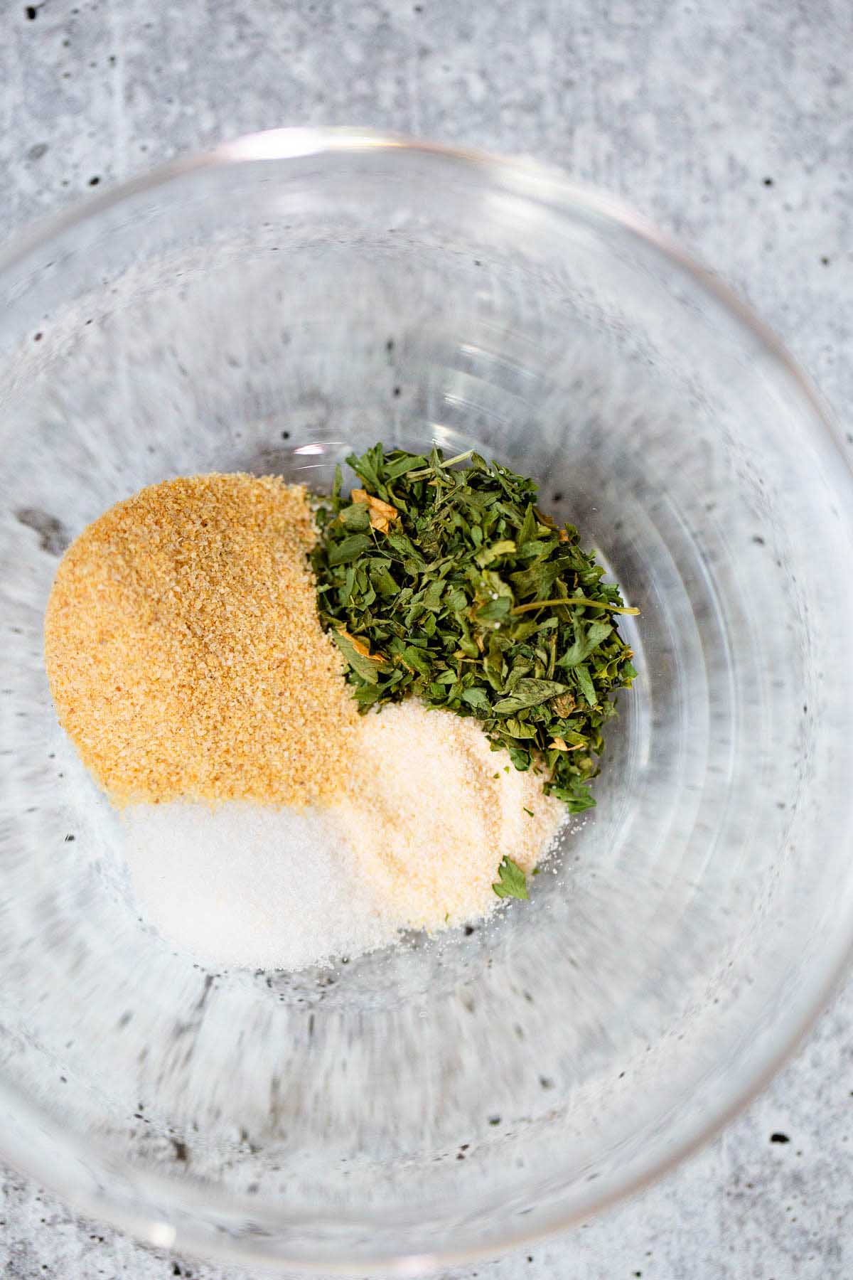 Spices in a bowl - garlic powder, salt, onion powder, dried parsley.