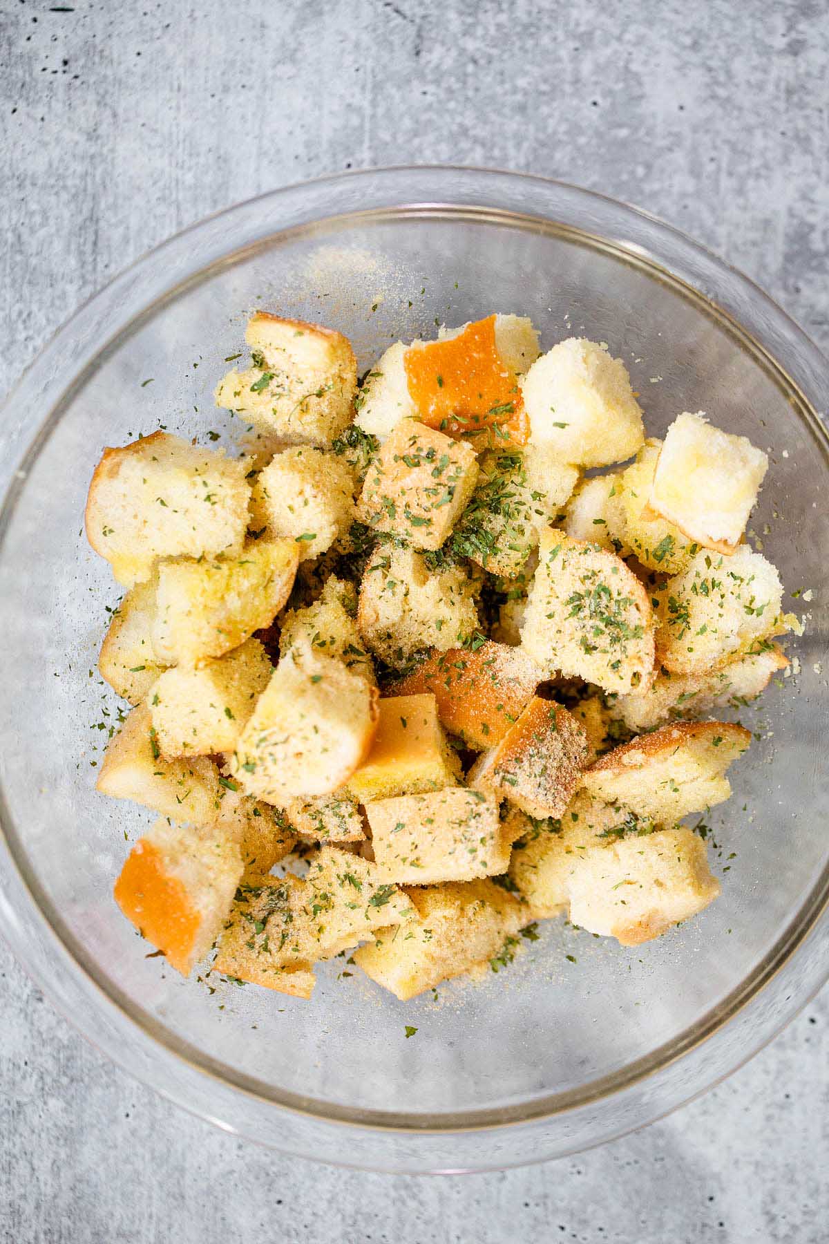 Bread chunks in a glass bowl with spices.