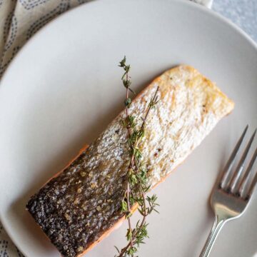 Air fried salmon on plate with the skin up.