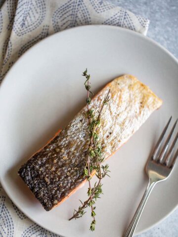 Air fried salmon on plate with the skin up.