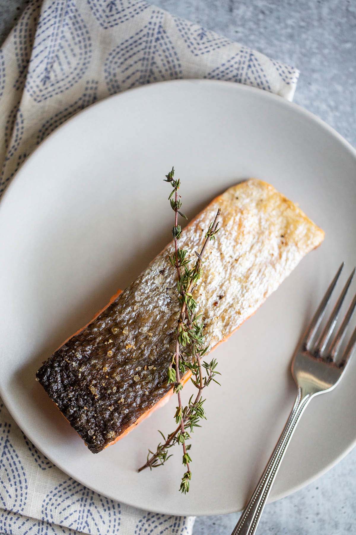 Air fried salmon on plate with the skin up.