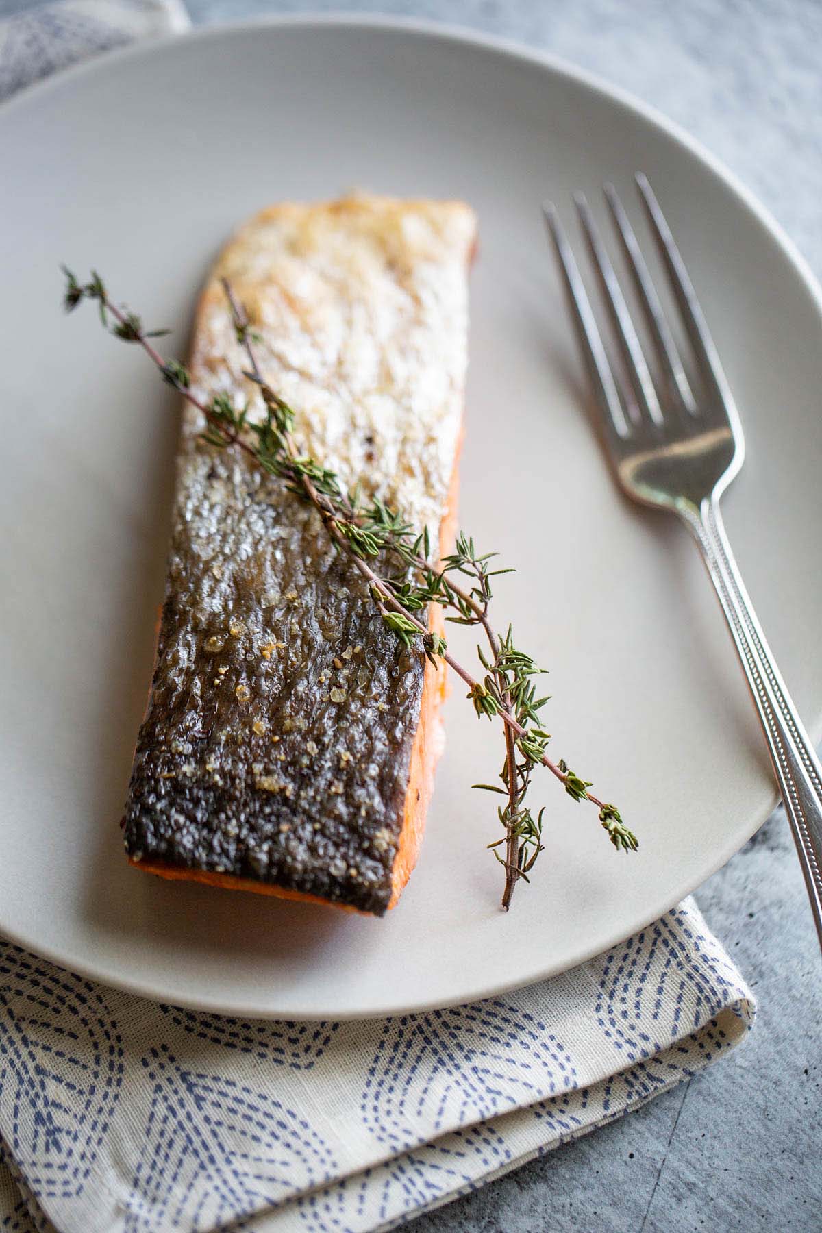 Salmon on a plate with a sprig of fresh thyme.