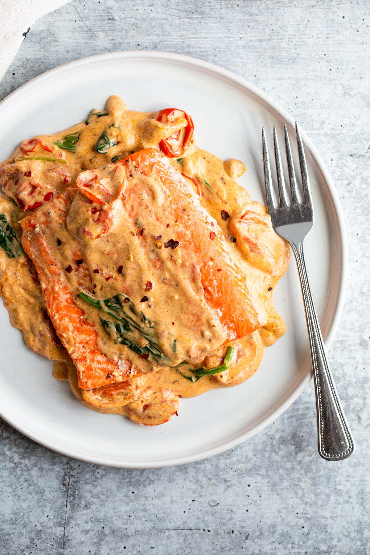 Salmon with a Tuscan cream sauce on a white plate.