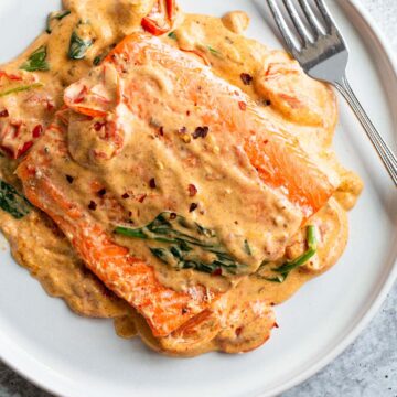 Salmon with a Tuscan cream sauce on a white plate.