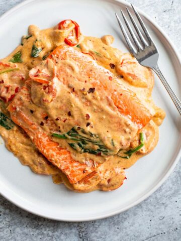 Salmon with a Tuscan cream sauce on a white plate.