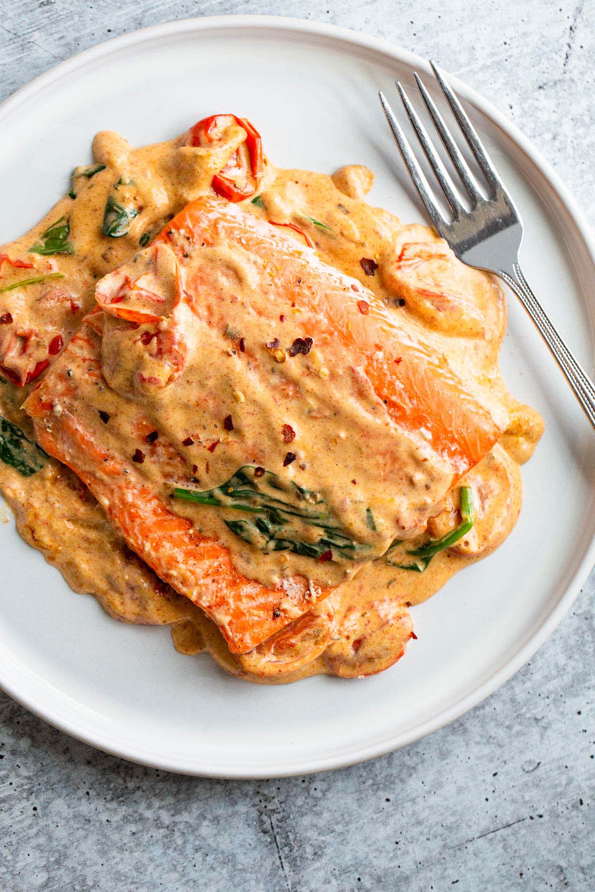 Salmon with a Tuscan cream sauce on a white plate.