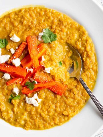 Red lentil dahl topped with roasted carrots, feta, and cilantro.