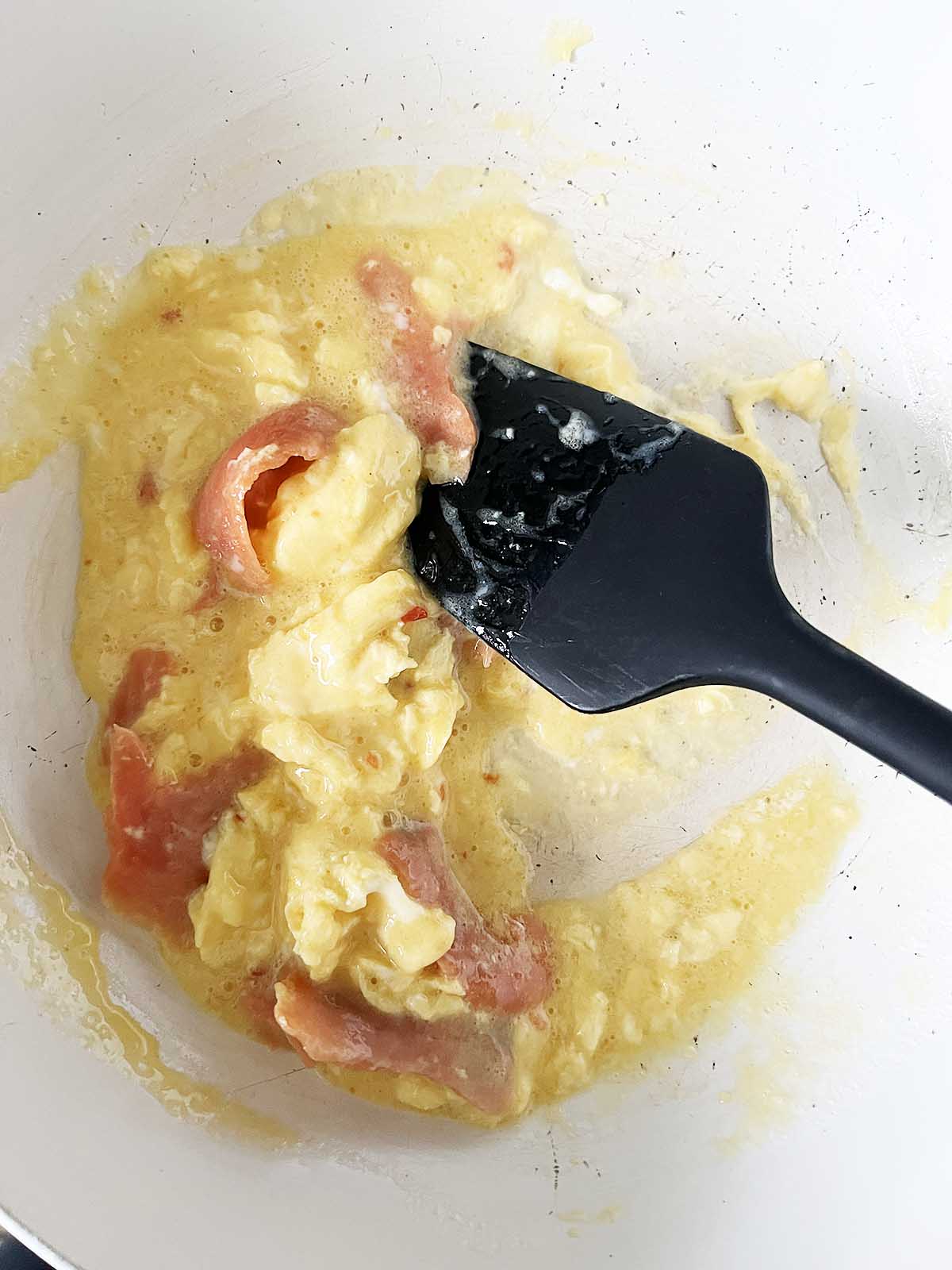 smoked salmon and scrambled eggs cooking in a pan.