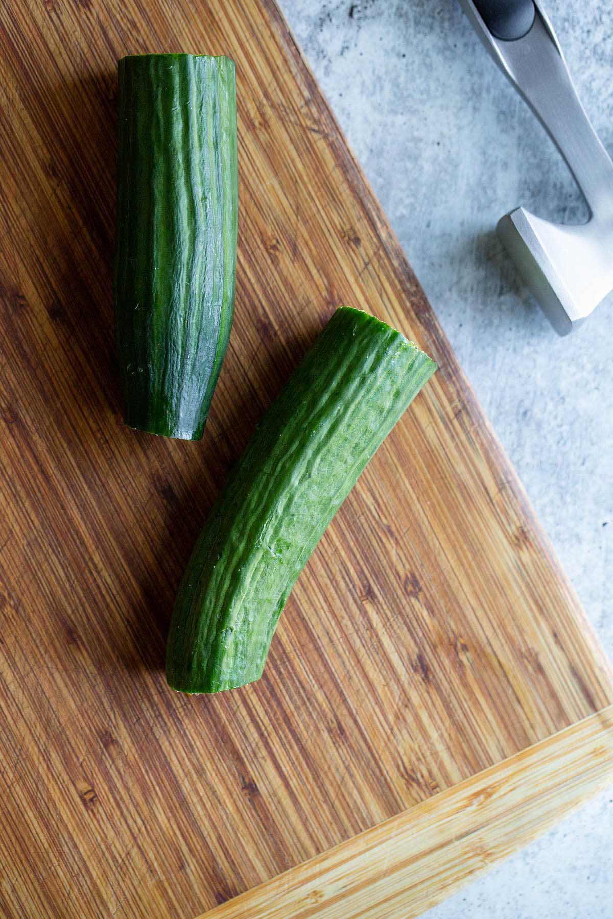 Two pieces of cucumber on a cutting board.