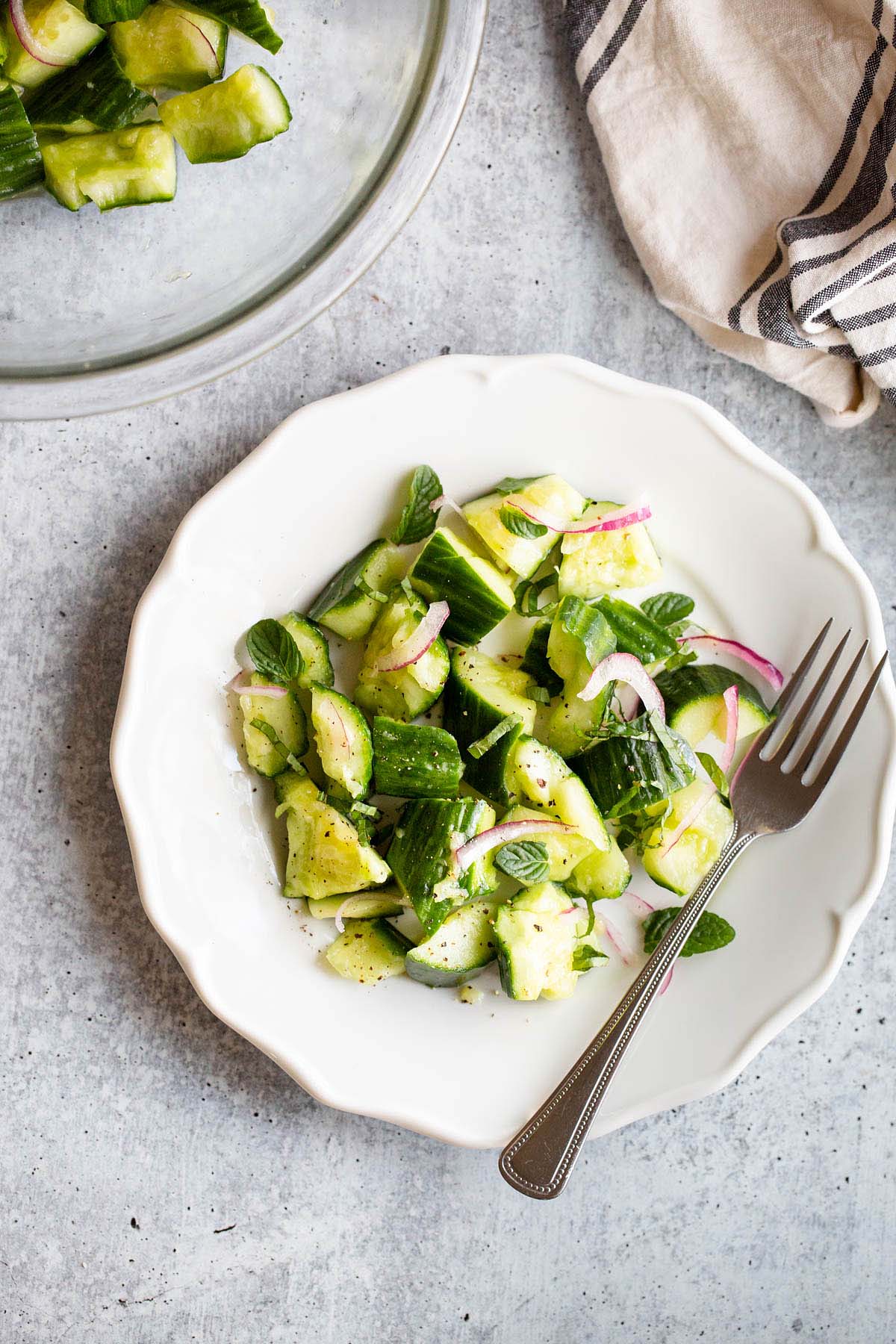 cucumber mint salad on a plate with a fork from above.