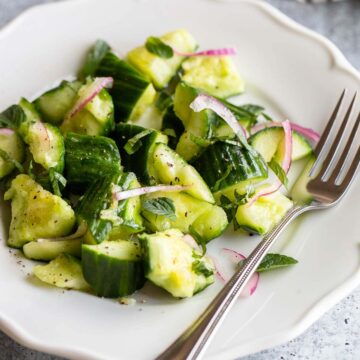 cucumber mint salad on a plate with a fork.