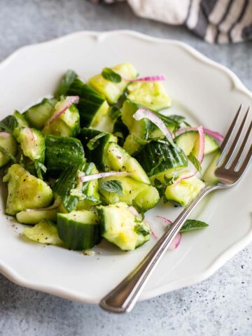 cucumber mint salad on a plate with a fork.