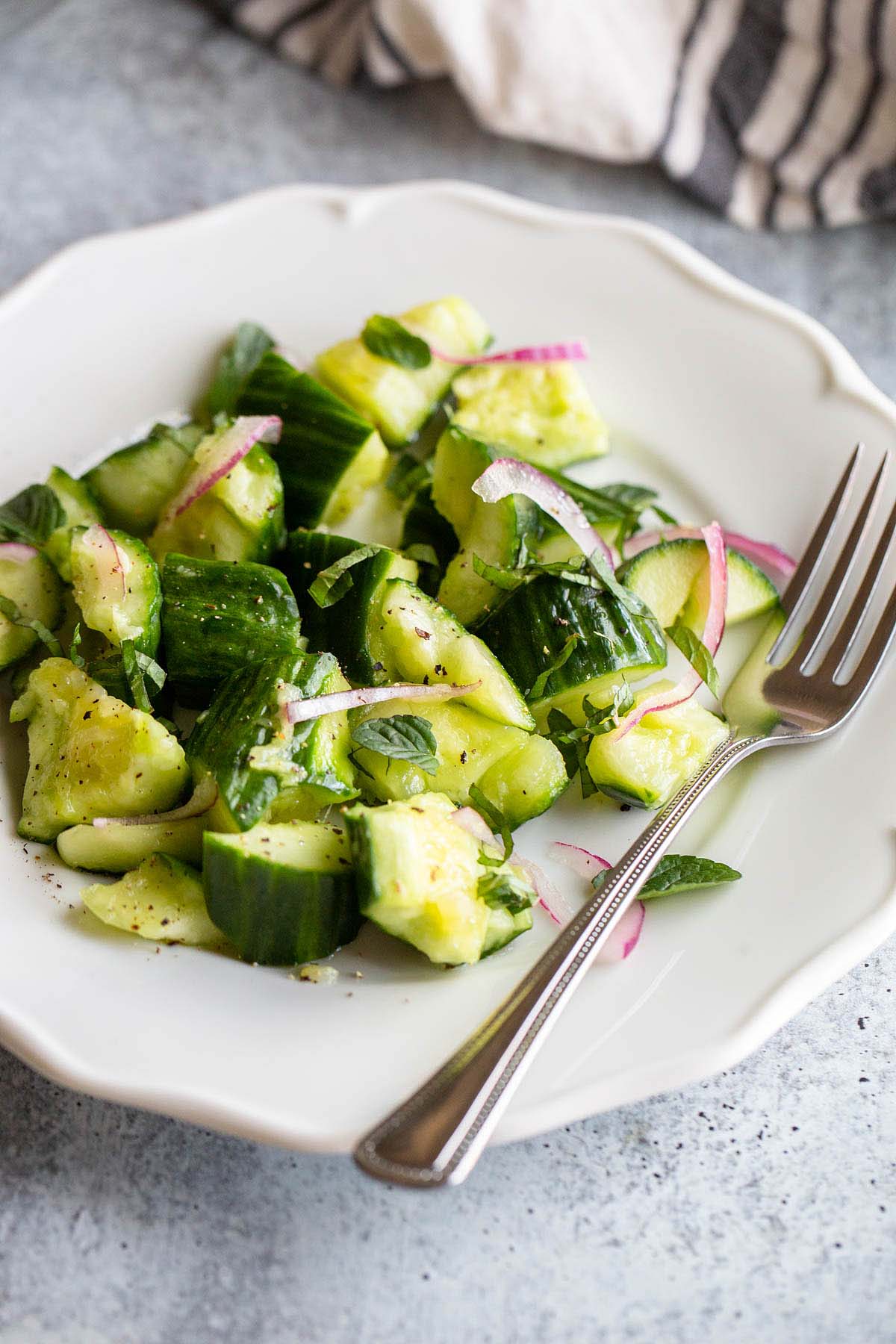 cucumber mint salad on a plate with a fork.