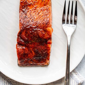 Cooked salmon on a white plate with a fork.