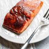 Cooked salmon on a white plate with a fork.