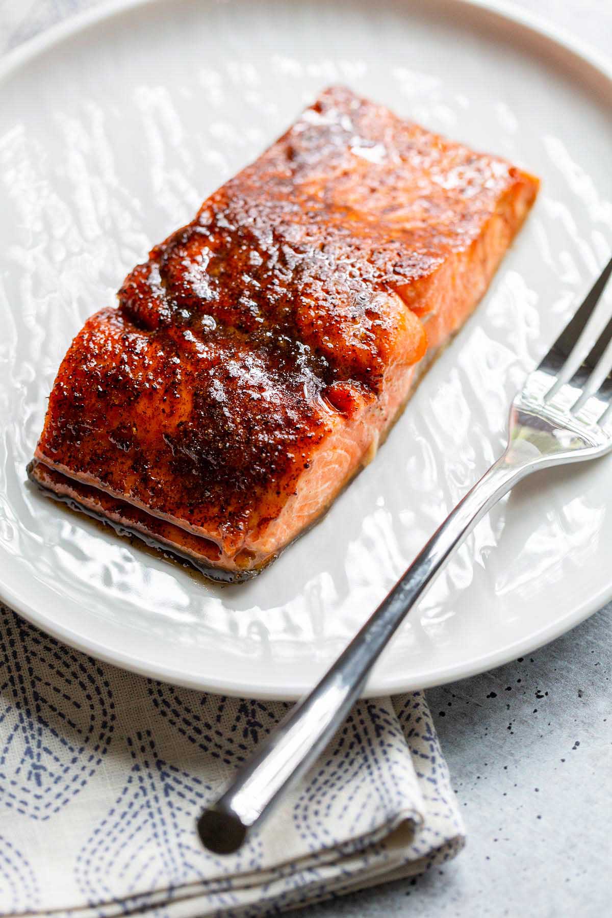 Cooked salmon on a white plate with a fork.