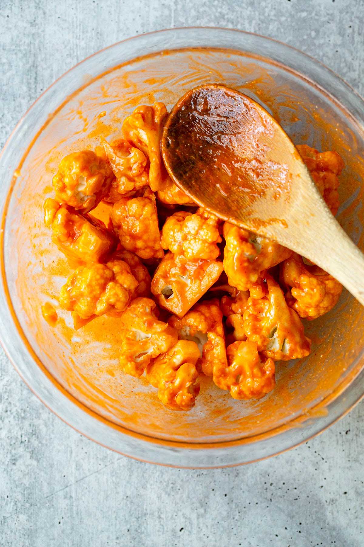 Cauliflower in buffalo sauce in a glass bowl.