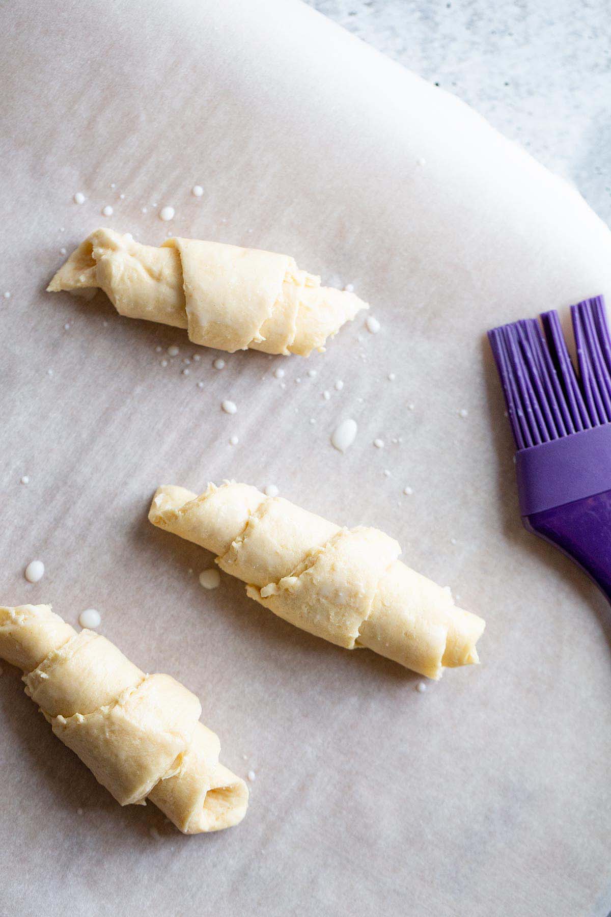 Brushing crescent rolls with milk.