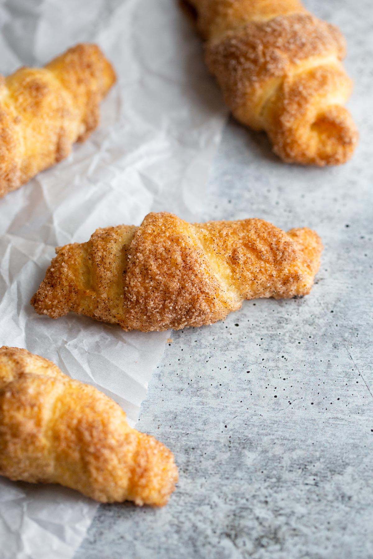 Cooked cinnamon sugar croissants on parchment paper.