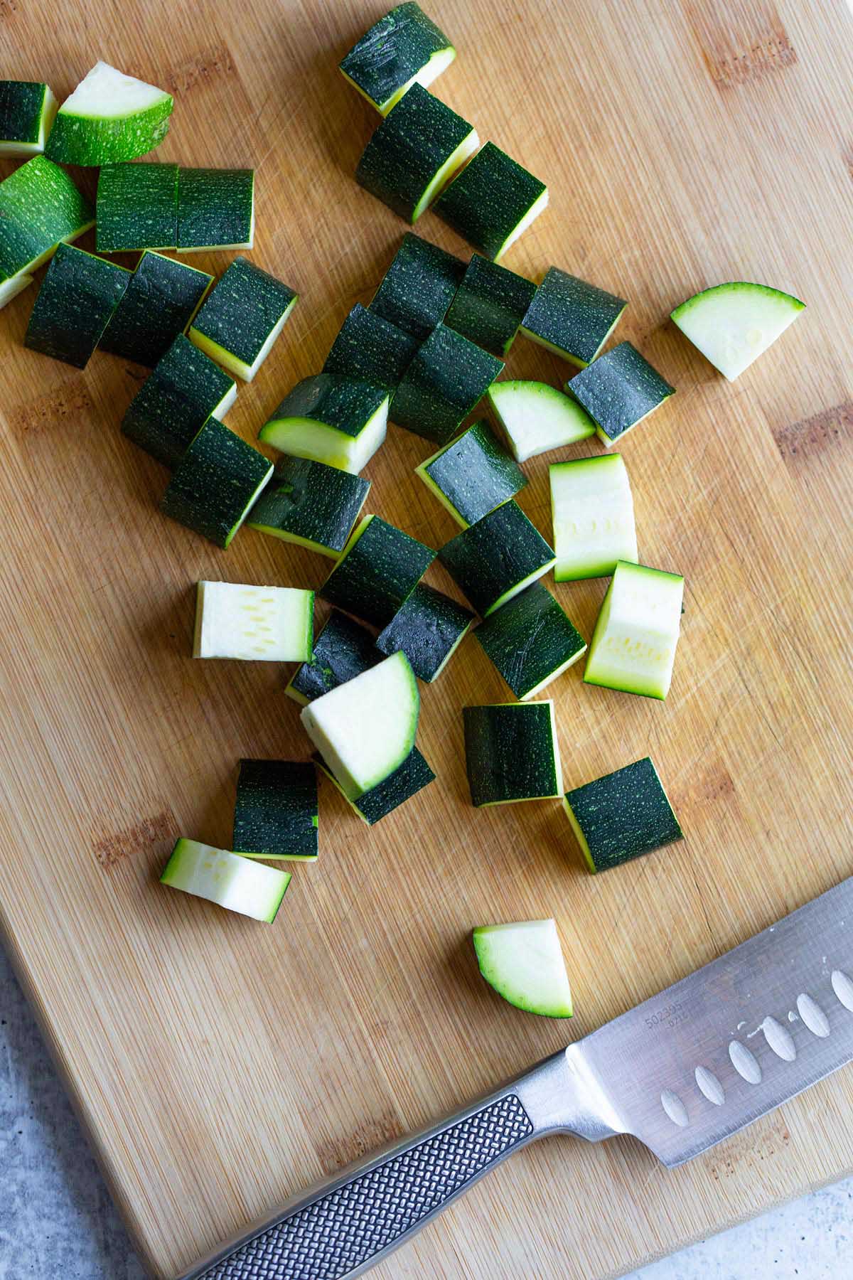 Chopped zucchini cubes on a cutting board.