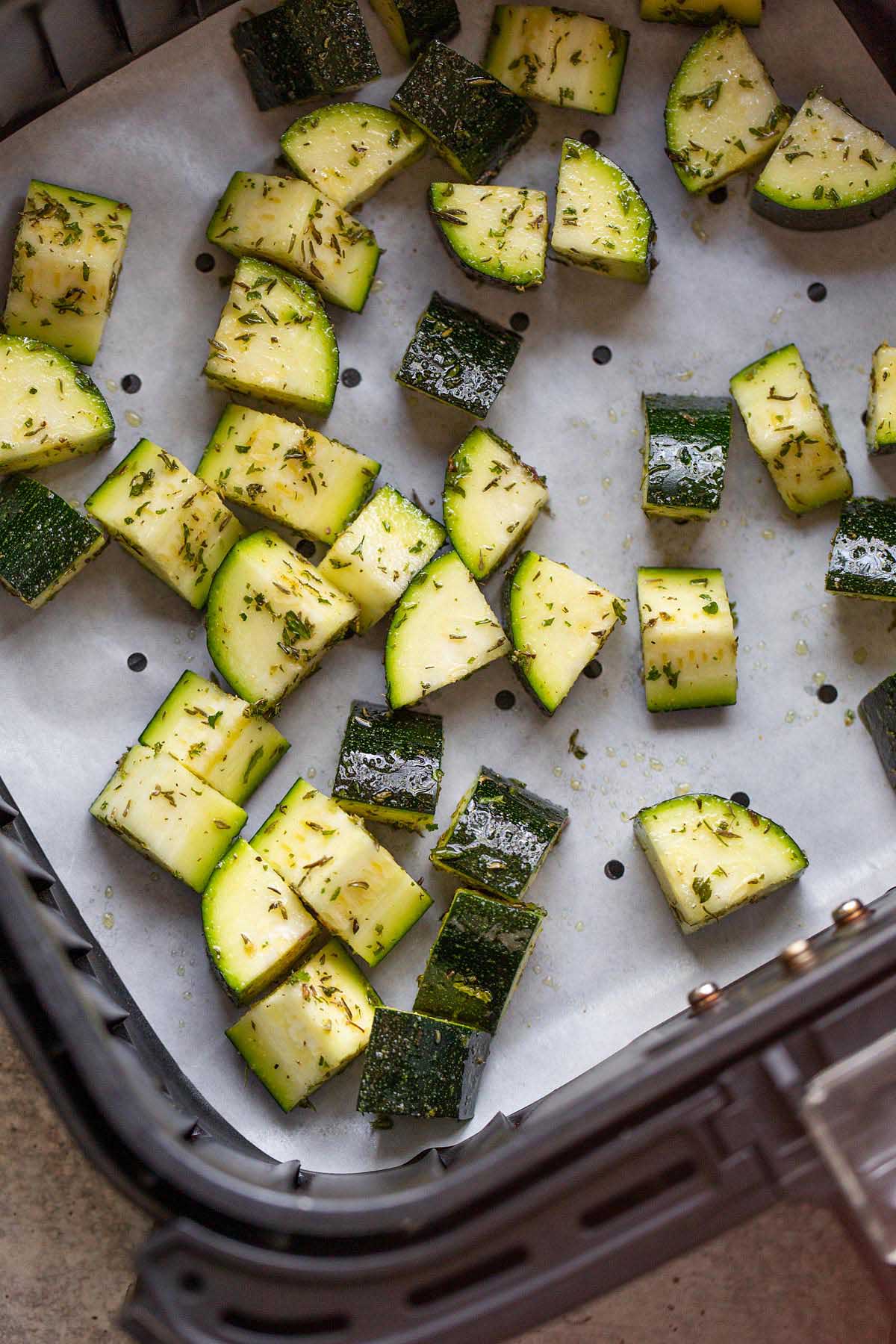 Raw zucchini in an air fryer basket.