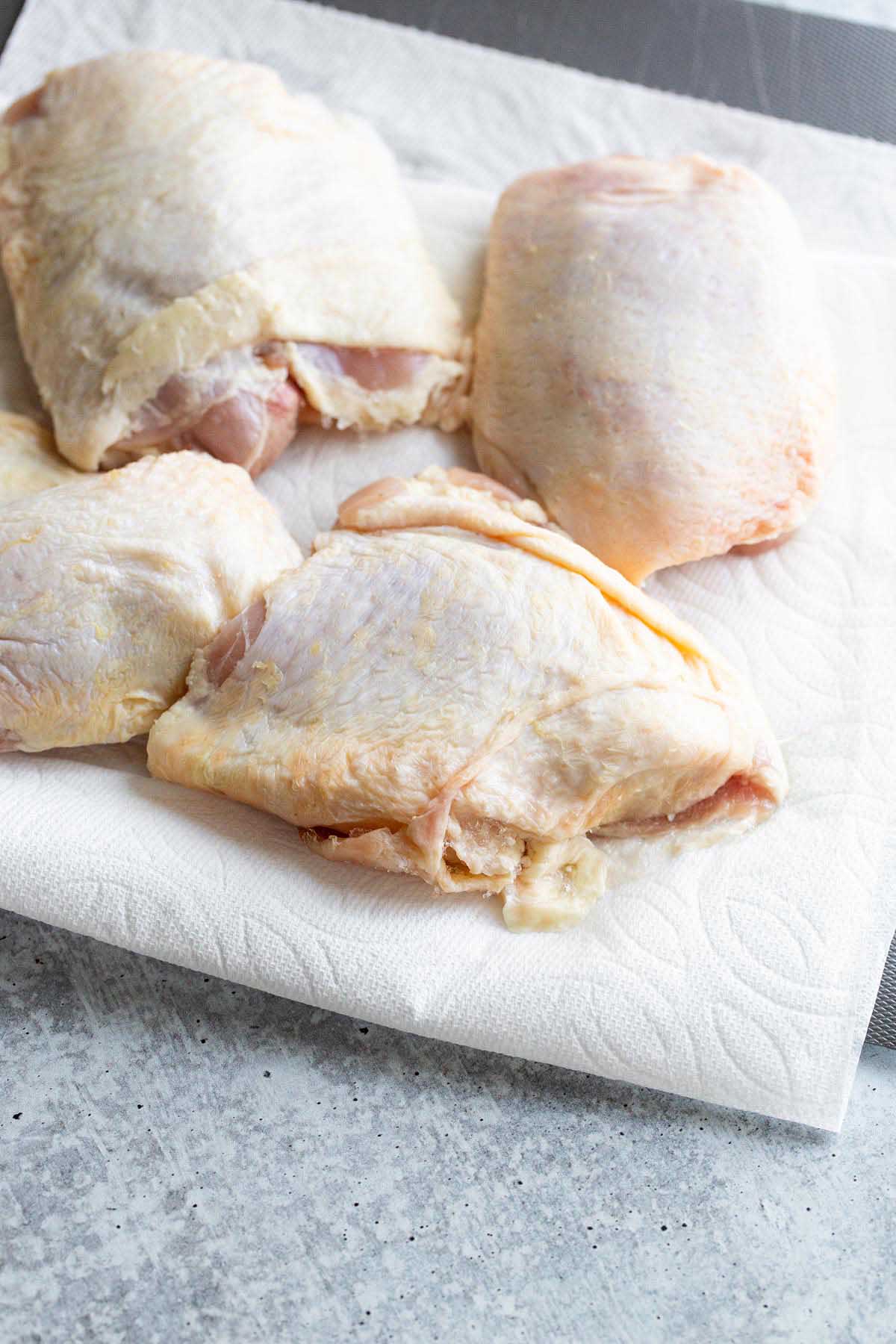 Raw chicken thighs on a paper towel.