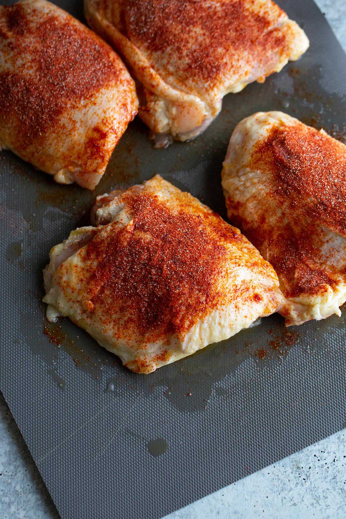 Chicken thighs on a cutting board with paprika.