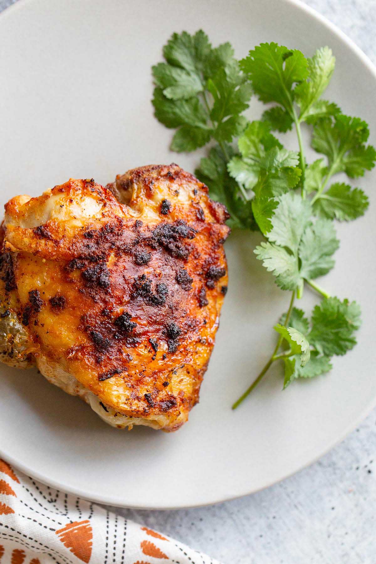 Air Fryer chicken thigh on a plate with a side of parsley.