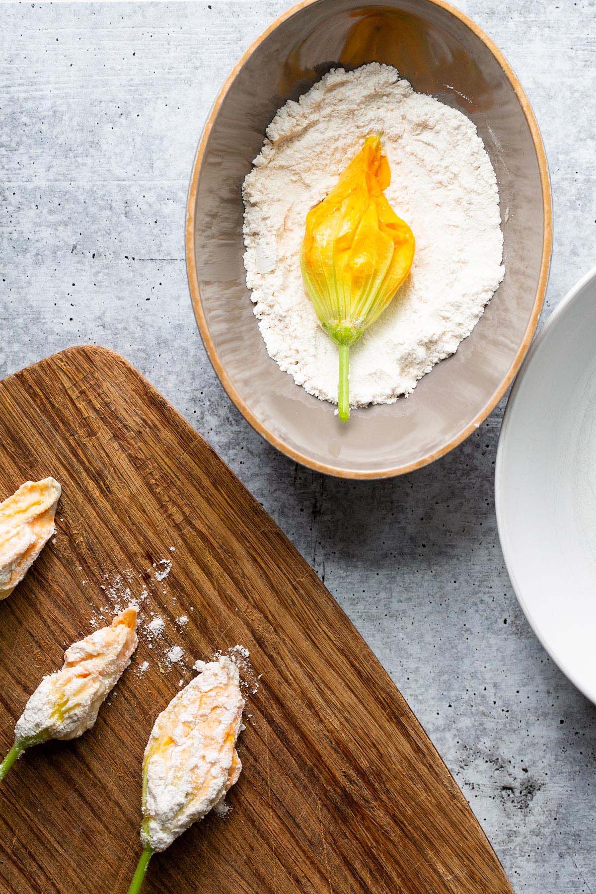 Dipping a zucchini flower in flour.